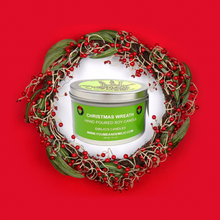 Christmas Wreath Soy Candle in a glass jar, surrounded by pinecones, evergreen sprigs, and festive holiday décor, creating a warm and cozy ambiance.