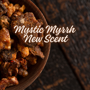 A hand holding the Mystic Myrrh Fragrance Oil bottle, highlighting the amber glass and modern black label, set against a rustic wooden surface.