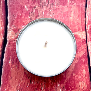 A burning Mystic Myrrh Soy Candle placed on a rustic wooden table, surrounded by natural elements, evoking a serene and grounding atmosphere.